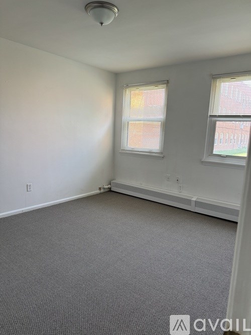 A room with a carpeted floor and two windows.