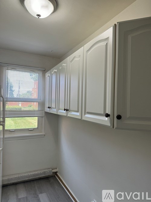 A room with white cabinets and a window with blinds.
