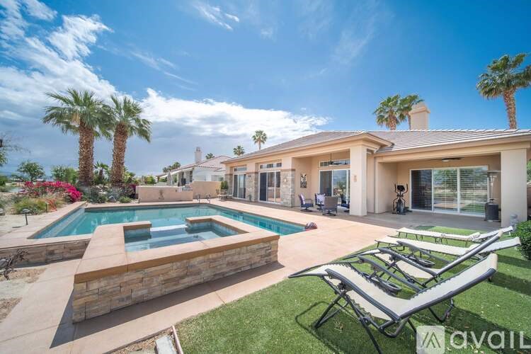 A house with a pool and palm trees in front.