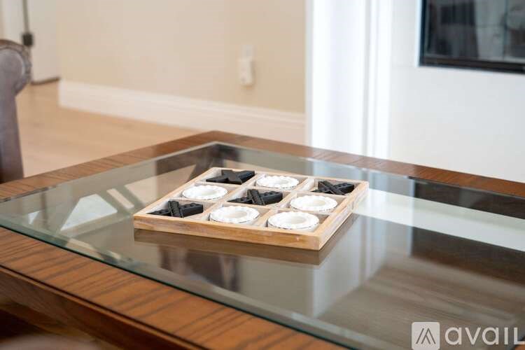 A set of six black dominoes are arranged on a wooden board on a glass table.