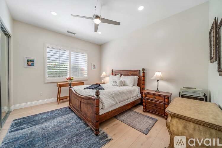 A bedroom with a large bed, a small bed, and a ceiling fan.