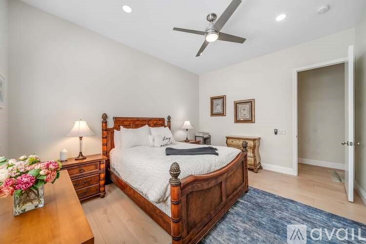 A bedroom with a large bed, a dresser, and a ceiling fan.