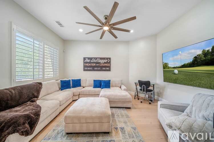 A living room with a white couch, a brown couch, a rug, and a ceiling fan.