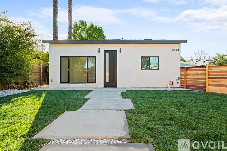 A modern house with a white exterior and a black door is for sale.