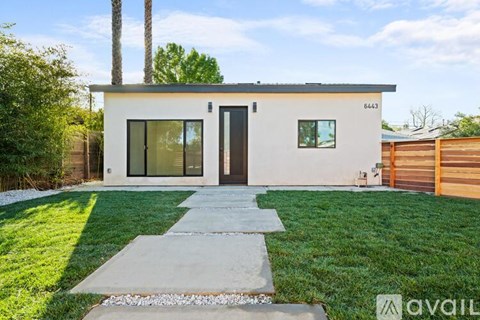 A modern house with a white exterior and a black door is for sale.