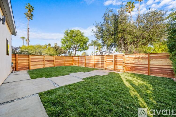 A backyard with a wooden fence and a concrete patio.