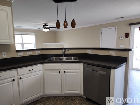 A kitchen with white cabinets and a black countertop.