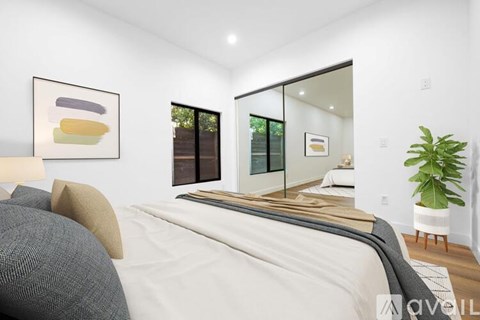 A modern bedroom with a large bed and a plant.
