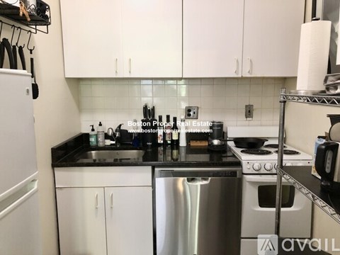 A kitchen with white cabinets and black countertops.