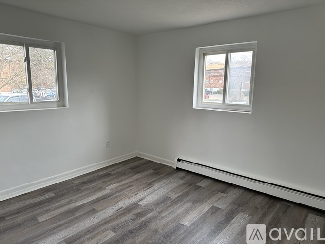 A room with grey flooring and two windows.