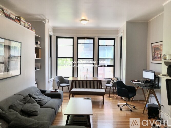 A living room with a grey couch, a wooden coffee table, and a desk with a computer.