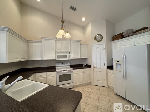 A kitchen with white cabinets and a black countertop.