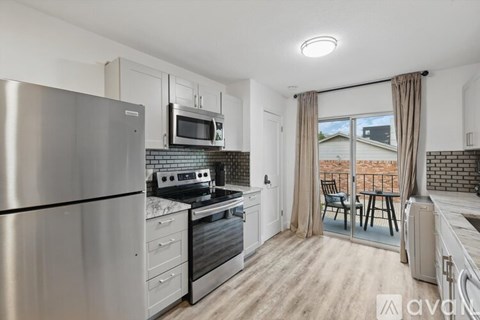 A modern kitchen with stainless steel appliances and a dining area with a view.