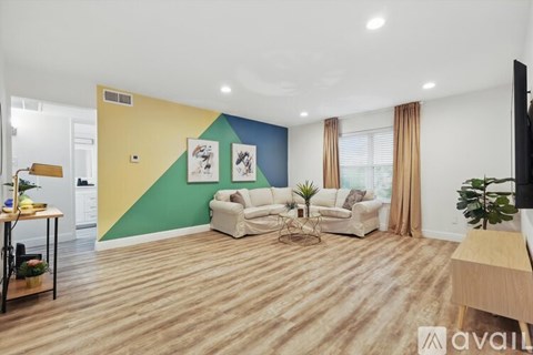 A living room with a white couch and a yellow and green wall.