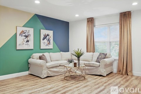 A living room with a white sofa, a coffee table, and two framed pictures on the wall.