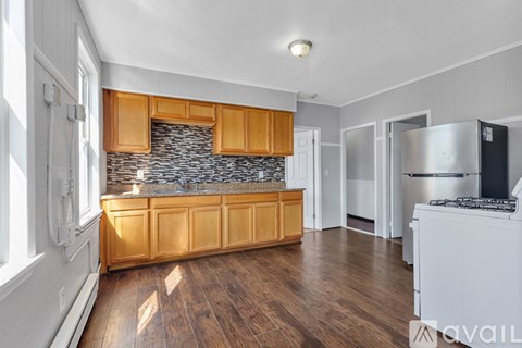 A kitchen with wooden cabinets and a stone backsplash.