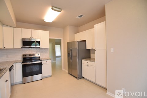 A kitchen with white cabinets and appliances.
