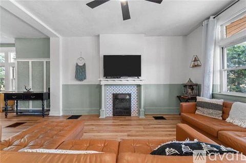 A living room with a brown leather couch and a fireplace.