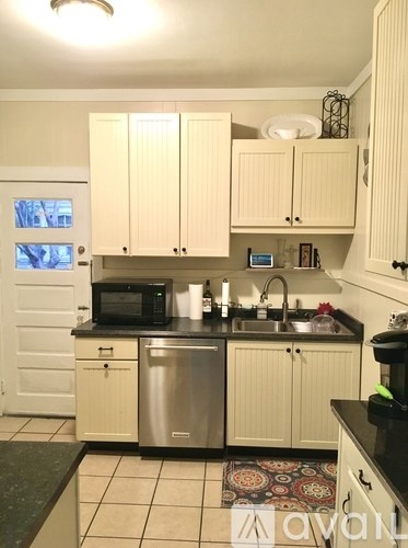 A kitchen with white cabinets and a black counter top.
