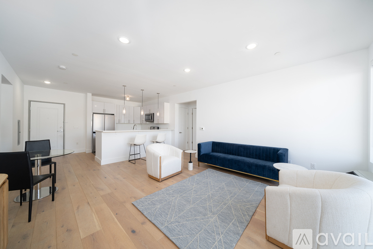A living room with a blue couch and a white rug.