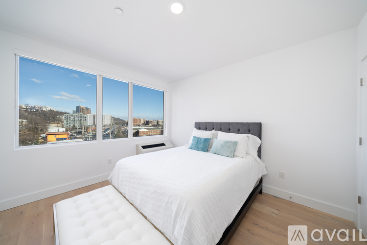 A bedroom with a large bed and a view of the city through the windows.