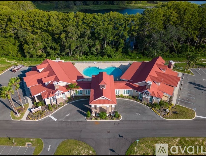 A large building with a red roof and a pool in front.