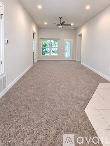 A spacious room with a carpeted floor and a ceiling fan.