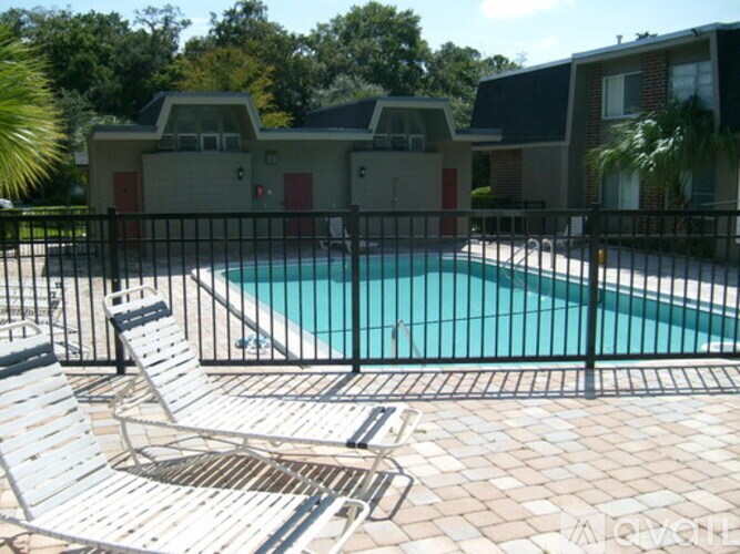 A pool surrounded by a black fence and chairs.