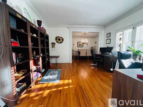 A living room with a wooden floor and a large bookshelf filled with books.