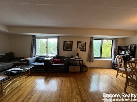A living room with a couch, chair, and a table with a lamp on it.