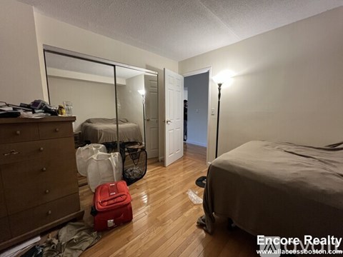A bedroom with a bed, a dresser, and a mirror.