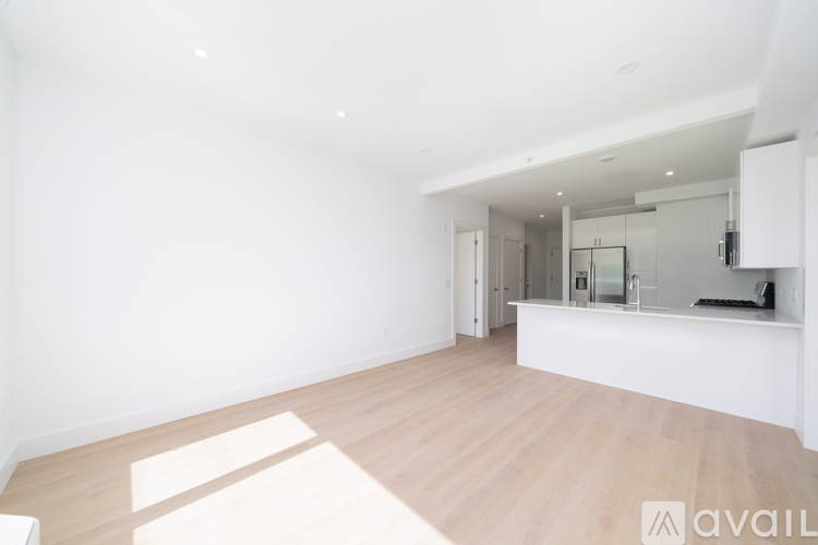 A spacious, empty room with wooden flooring and white walls.