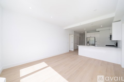 A spacious, empty room with wooden flooring and white walls.