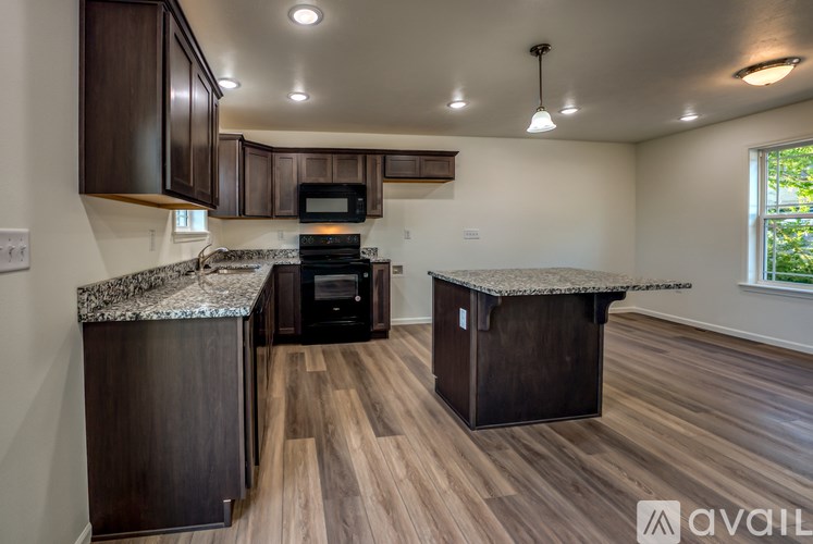 A kitchen with dark wood cabinets and a granite countertop.