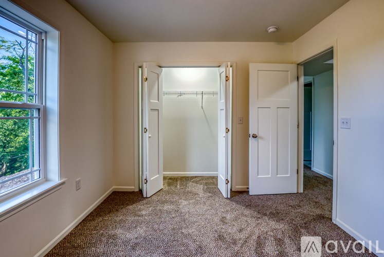 A bedroom with a carpeted floor and a window.