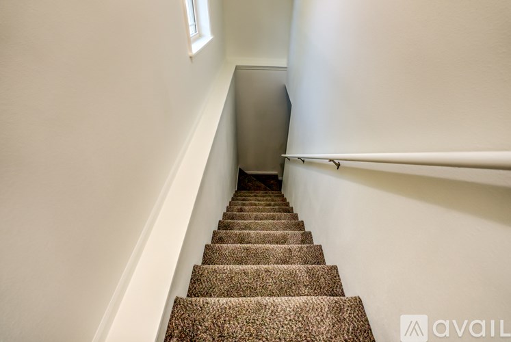 A staircase with a carpeted runner and a metal handrail.