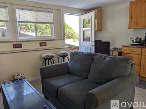 A grey couch sits in a living room with a glass table in front of it.