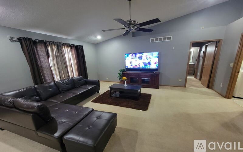 A living room with a black leather sofa and a television on the wall.