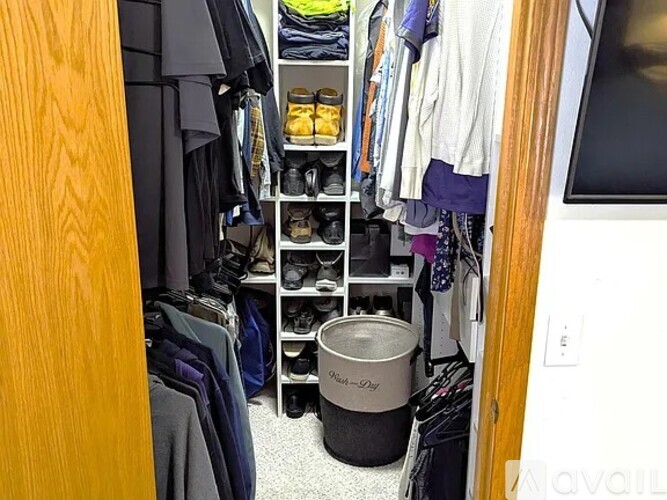A small closet with a lot of clothes and shoes.