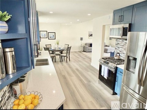 A kitchen with a refrigerator, sink, and dining table.