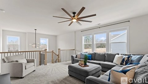 A living room with a grey sofa and a ceiling fan.