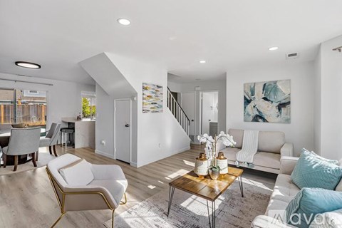 A living room with a white couch, a coffee table, and a painting on the wall.