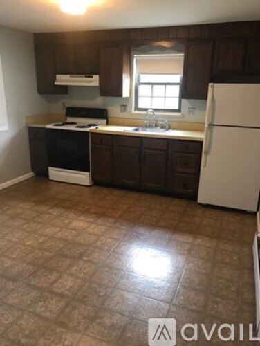 A kitchen with brown cabinets and a white refrigerator.