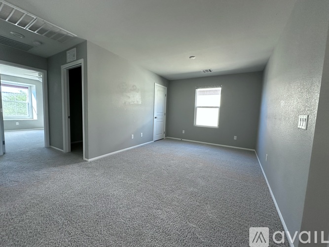 A spacious room with grey carpeting and a window.