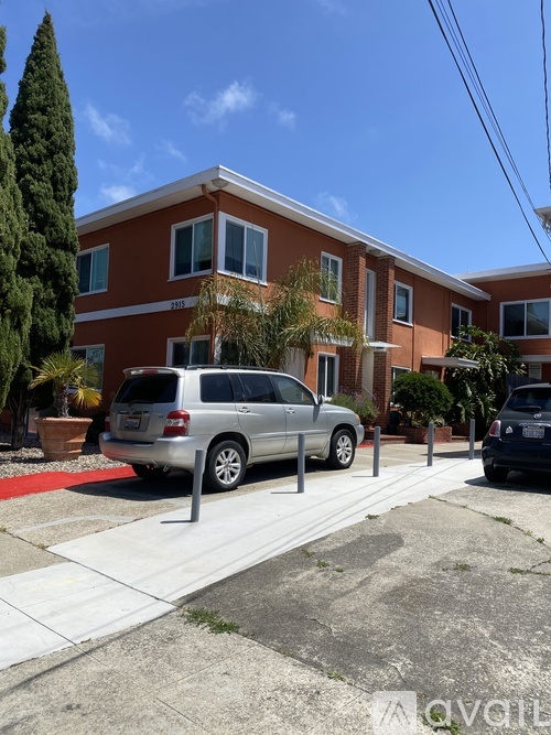 A silver minivan is parked in front of a red brick building.