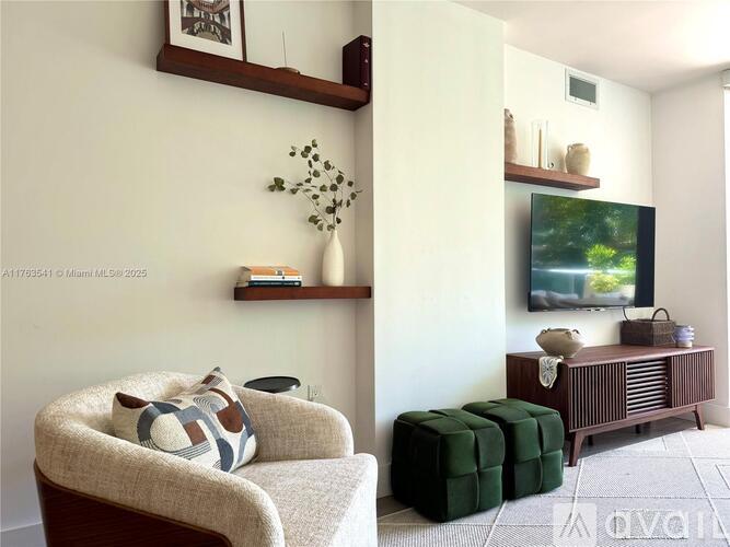 A living room with a couch, ottoman, and television.