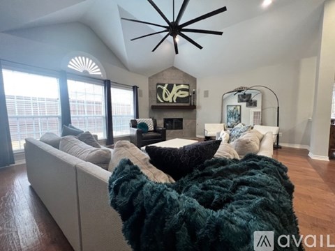 A living room with a white couch and a green blanket on it.