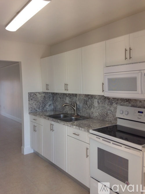 A kitchen with granite countertops and white cabinets.