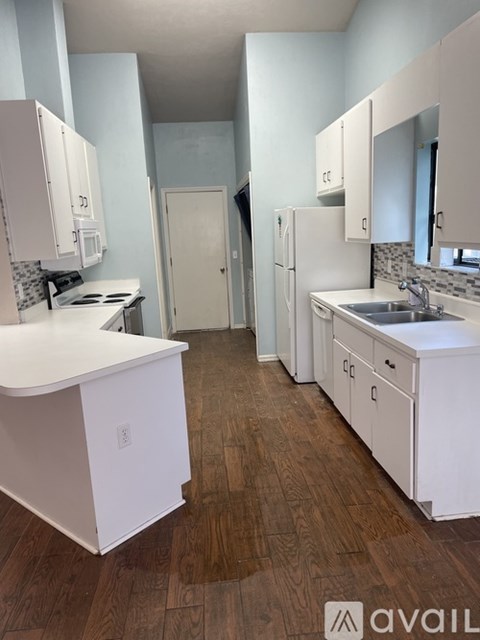 A kitchen with white cabinets and a wooden floor.