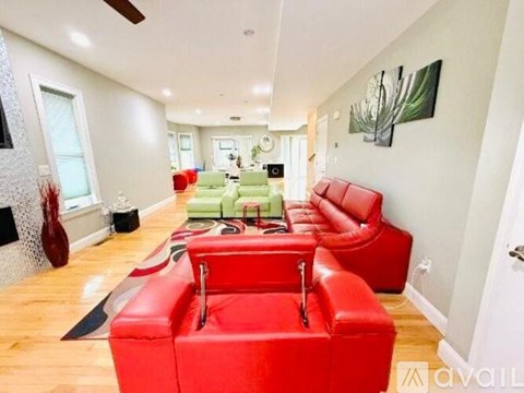 A living room with red couches and a green couch in the background.